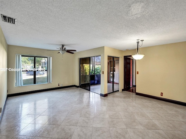 empty room featuring ceiling fan, a textured ceiling, and light tile patterned floors