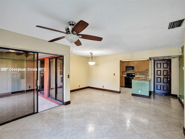 tiled empty room featuring ceiling fan and a textured ceiling