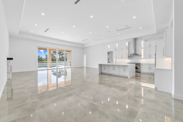 unfurnished living room with light tile patterned floors, a raised ceiling, and sink