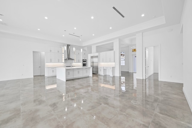 unfurnished living room featuring a raised ceiling, light tile patterned flooring, and sink