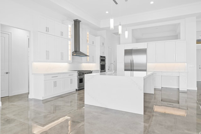 kitchen with wall chimney exhaust hood, a center island with sink, white cabinets, high quality appliances, and a tray ceiling