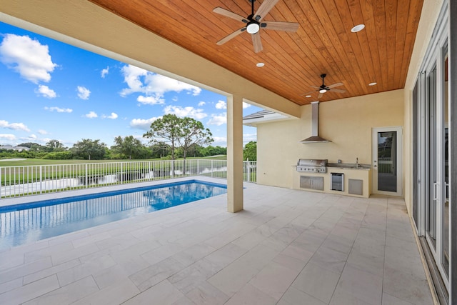 view of pool with sink, an outdoor kitchen, a patio area, ceiling fan, and a grill