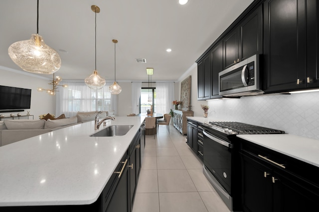 kitchen with backsplash, an island with sink, ornamental molding, sink, and range with gas stovetop