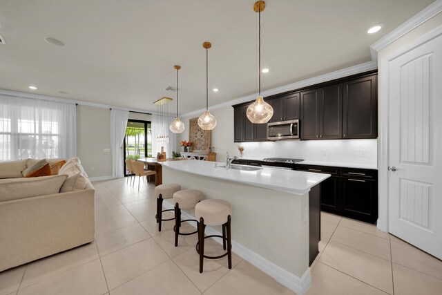 kitchen with backsplash, a kitchen island with sink, light tile patterned floors, and sink