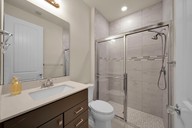 bathroom with toilet, vanity, and a shower with shower door