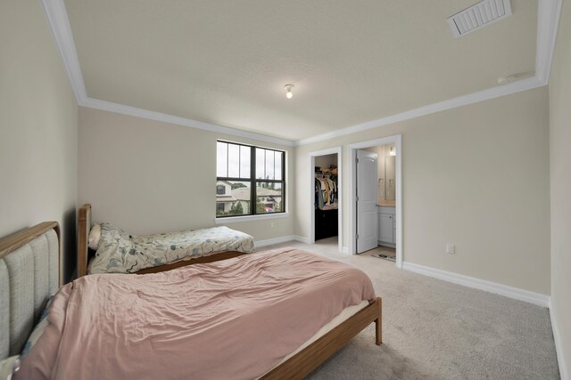 carpeted bedroom with a closet, crown molding, connected bathroom, and a spacious closet