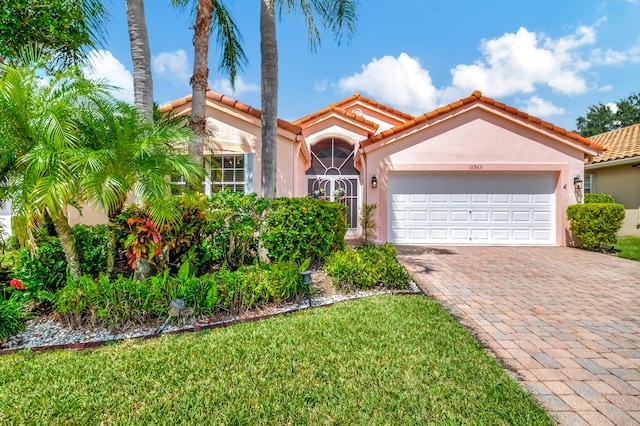 mediterranean / spanish house featuring a front yard and a garage