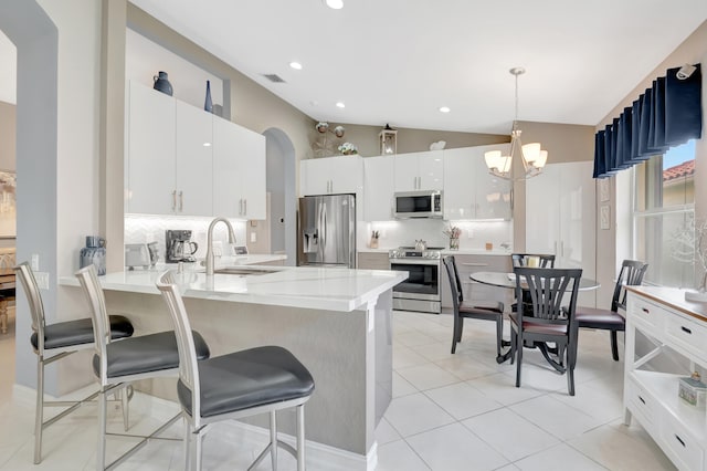 kitchen featuring stainless steel appliances, lofted ceiling, decorative light fixtures, and tasteful backsplash