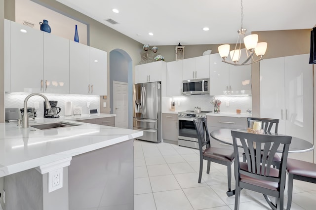 kitchen with appliances with stainless steel finishes, sink, backsplash, and decorative light fixtures