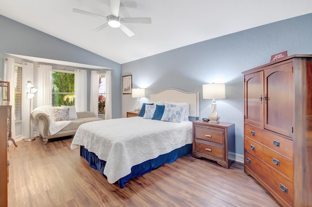 bedroom with ceiling fan, light hardwood / wood-style flooring, and lofted ceiling