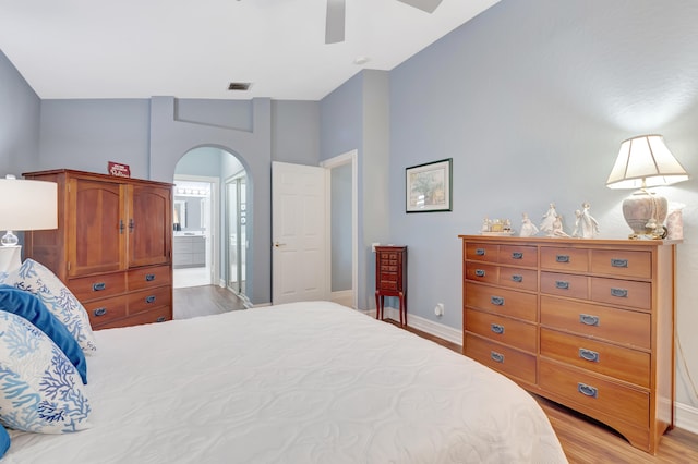 bedroom featuring ceiling fan, high vaulted ceiling, ensuite bath, and light hardwood / wood-style flooring