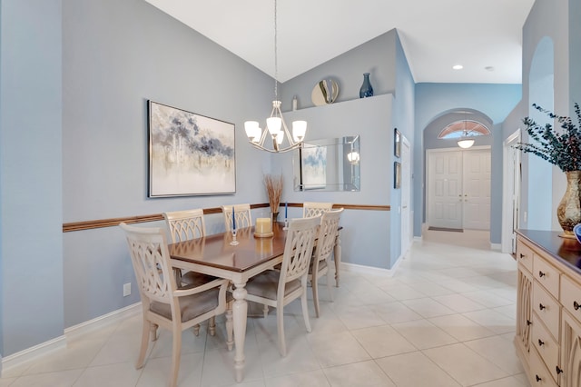 dining space with a notable chandelier, light tile patterned flooring, and lofted ceiling