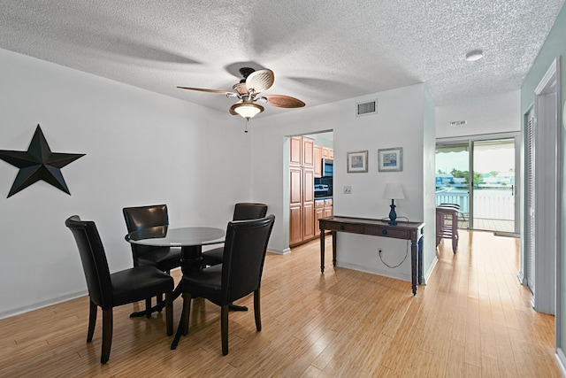 dining area featuring a textured ceiling, ceiling fan, and light hardwood / wood-style floors