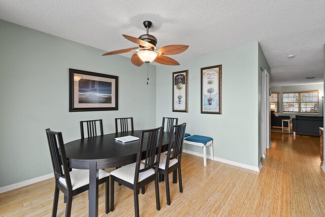 dining space with ceiling fan, light hardwood / wood-style floors, and a textured ceiling