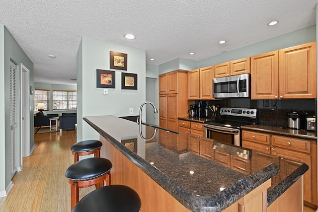 kitchen with backsplash, sink, appliances with stainless steel finishes, light hardwood / wood-style floors, and a textured ceiling