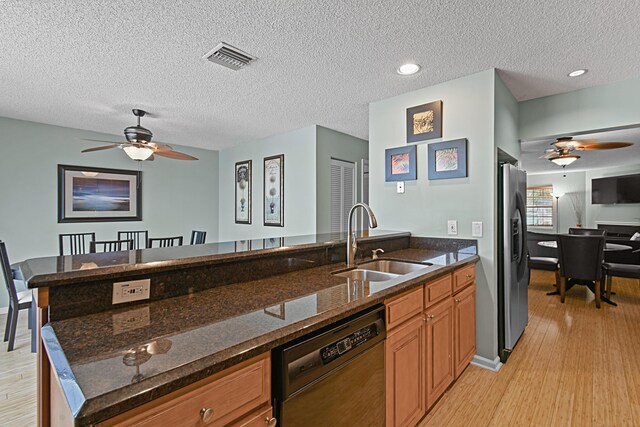 kitchen with sink, stainless steel fridge, black dishwasher, and dark stone counters