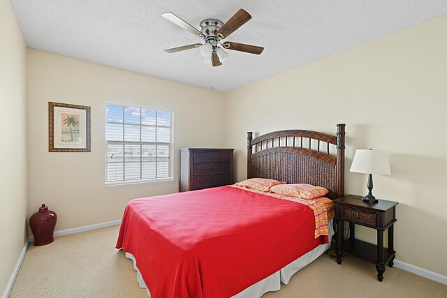 bedroom with a textured ceiling, ceiling fan, and light colored carpet