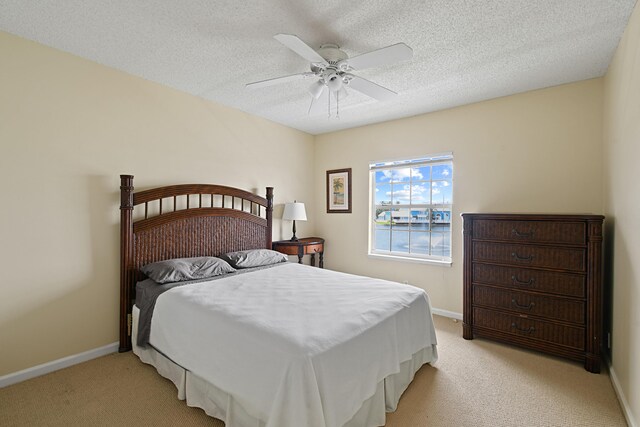 bedroom featuring ceiling fan, a textured ceiling, and light colored carpet