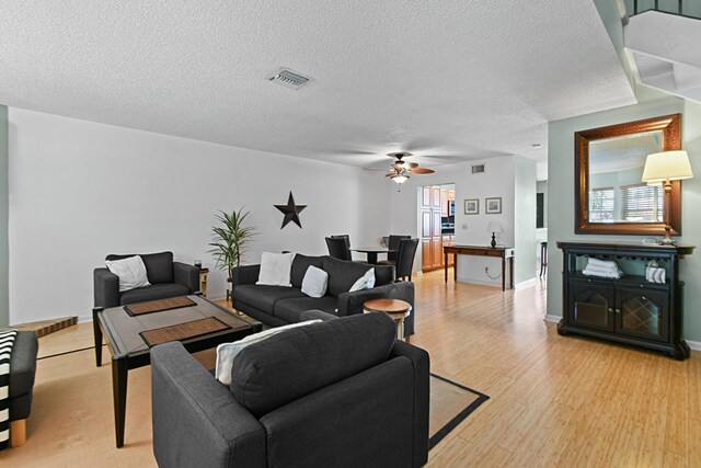 living room with ceiling fan, a textured ceiling, and light hardwood / wood-style flooring