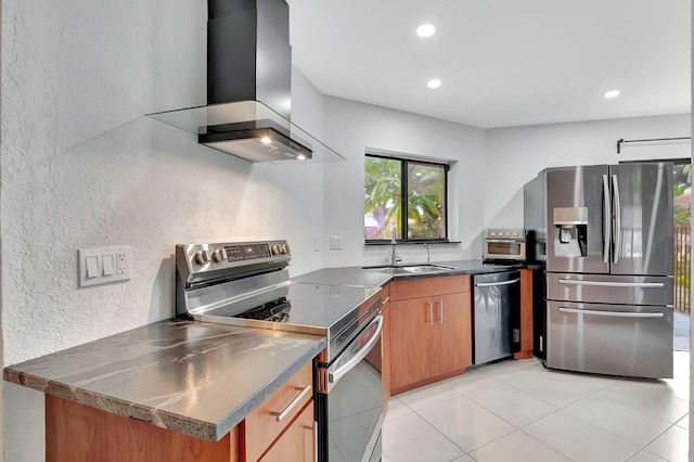 kitchen featuring wall chimney range hood, light tile patterned floors, appliances with stainless steel finishes, and sink