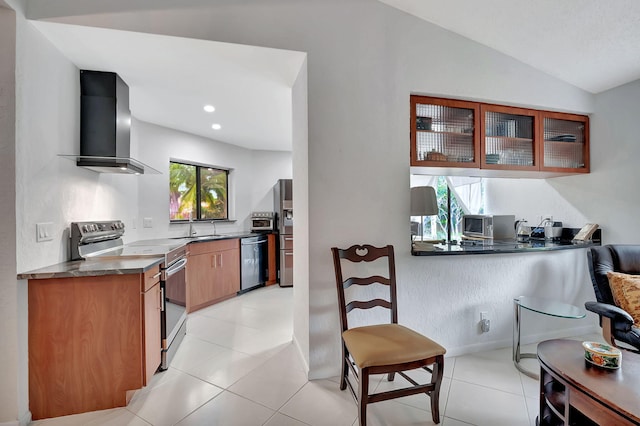 kitchen featuring wall chimney range hood, appliances with stainless steel finishes, light tile patterned floors, and plenty of natural light