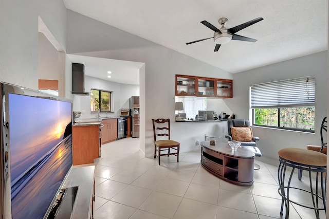 interior space featuring lofted ceiling, wall chimney exhaust hood, light tile patterned flooring, stove, and ceiling fan