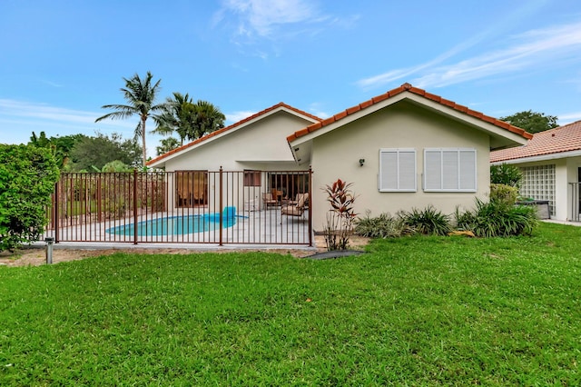 rear view of property featuring a patio, a fenced in pool, and a lawn