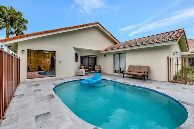 back of property with a fenced in pool and a patio area