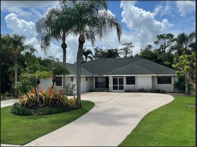 ranch-style house with a garage, driveway, a front lawn, and roof with shingles