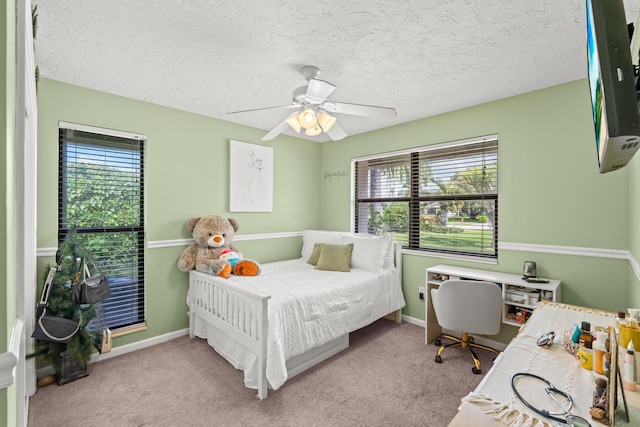 carpeted bedroom featuring multiple windows, a ceiling fan, baseboards, and a textured ceiling