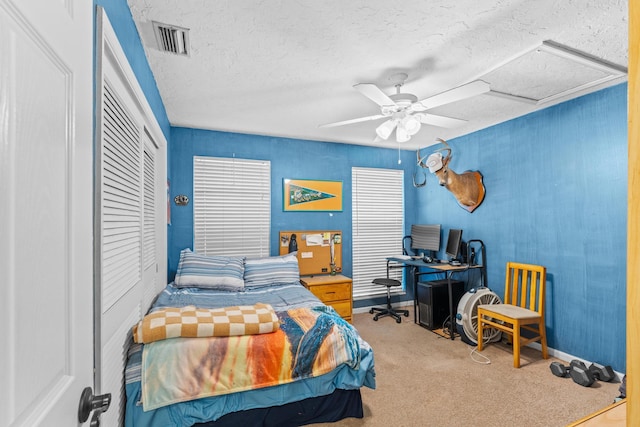 bedroom featuring visible vents, carpet flooring, a closet, a textured ceiling, and a ceiling fan