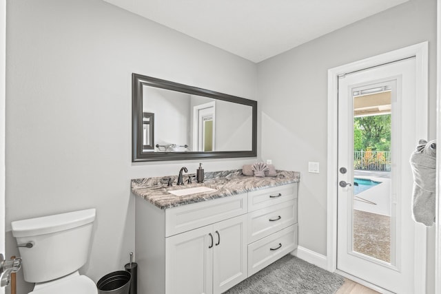 bathroom featuring toilet, vanity, and baseboards