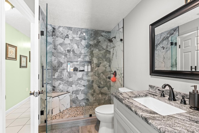 bathroom featuring toilet, a textured ceiling, a marble finish shower, baseboards, and vanity