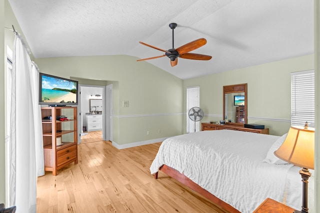 bedroom featuring baseboards, vaulted ceiling, light wood-style flooring, multiple windows, and a ceiling fan