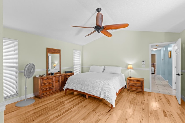 bedroom with light wood-type flooring, baseboards, ceiling fan, and vaulted ceiling