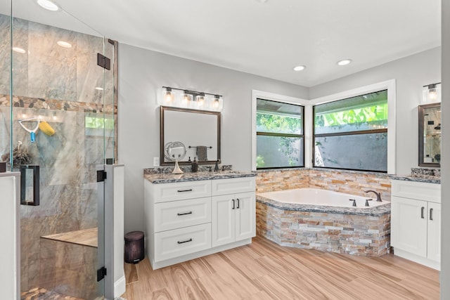 full bathroom featuring a stall shower, wood finished floors, recessed lighting, a bath, and vanity