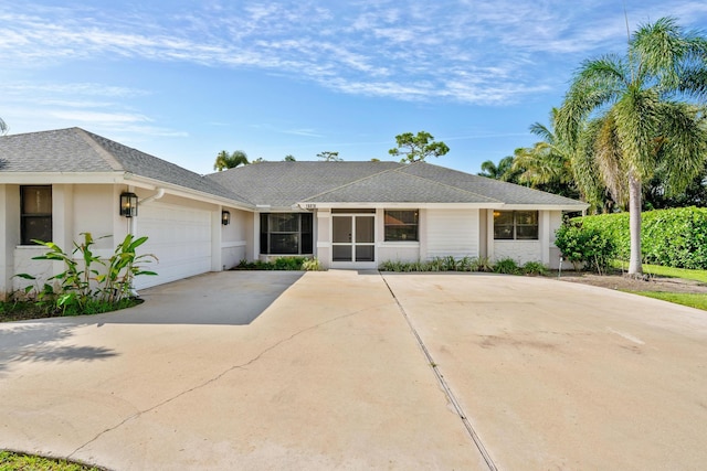 single story home with roof with shingles, an attached garage, driveway, and stucco siding