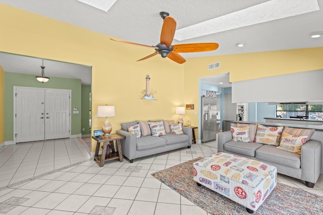 living room featuring light tile patterned floors, visible vents, ceiling fan, vaulted ceiling, and a textured ceiling