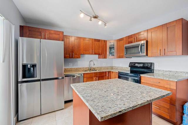 kitchen with appliances with stainless steel finishes, light tile patterned flooring, a center island, and light stone countertops