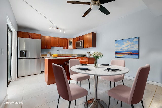 kitchen with light tile patterned floors, stainless steel appliances, light countertops, a kitchen island, and a sink