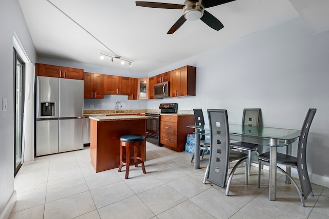 kitchen with a center island, appliances with stainless steel finishes, sink, ceiling fan, and a breakfast bar area