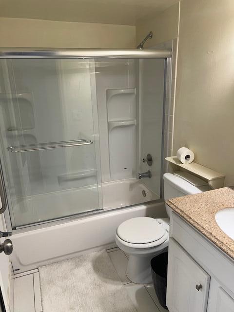 full bathroom featuring vanity, tile patterned flooring, toilet, and combined bath / shower with glass door