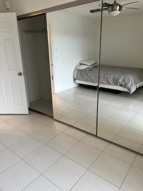 unfurnished bedroom featuring ceiling fan, a closet, and light tile patterned floors