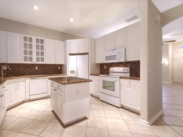 kitchen featuring light tile patterned floors, backsplash, a center island, and white appliances