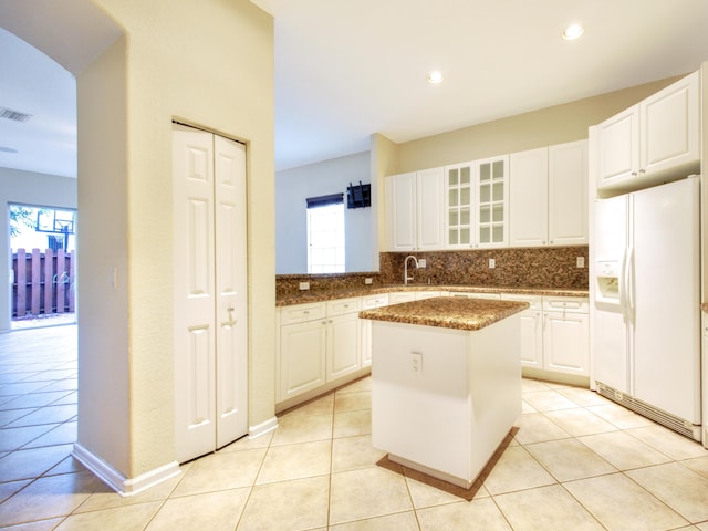 kitchen featuring a center island, white cabinets, light tile patterned floors, and white refrigerator with ice dispenser