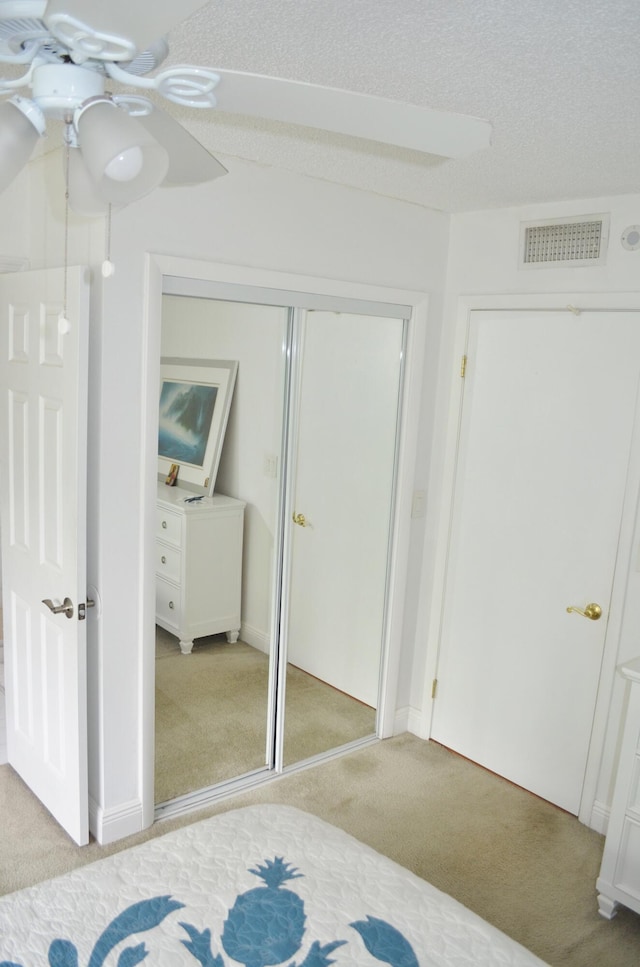 carpeted bedroom featuring a textured ceiling and ceiling fan