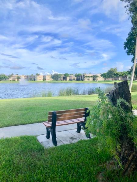 view of home's community with a water view and a yard