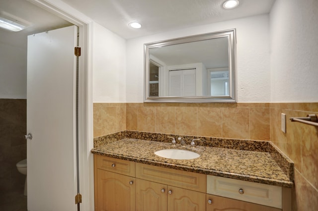 bathroom with tile walls, tasteful backsplash, vanity, and toilet