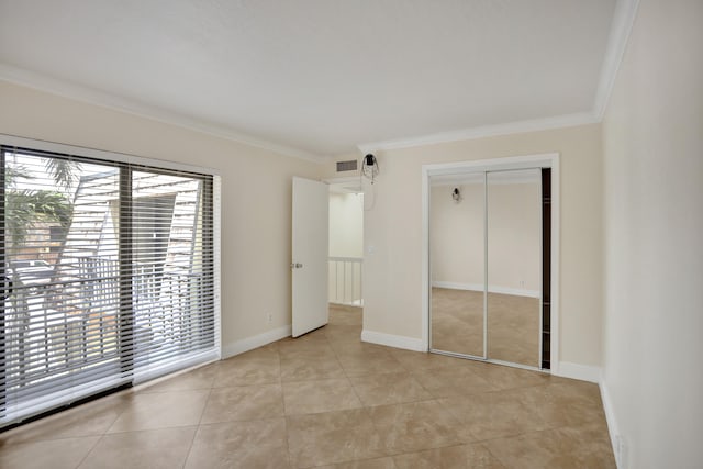 unfurnished bedroom with a closet, crown molding, and light tile patterned flooring