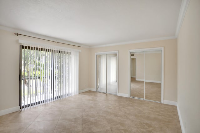 unfurnished bedroom featuring multiple closets, crown molding, and light tile patterned floors